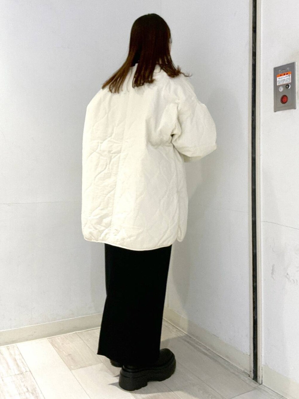 ホワイト系のブルゾン、ブラック系のブーツ、ブラック系のスカートを着用したレディースの秋コーディネートの2枚目の写真