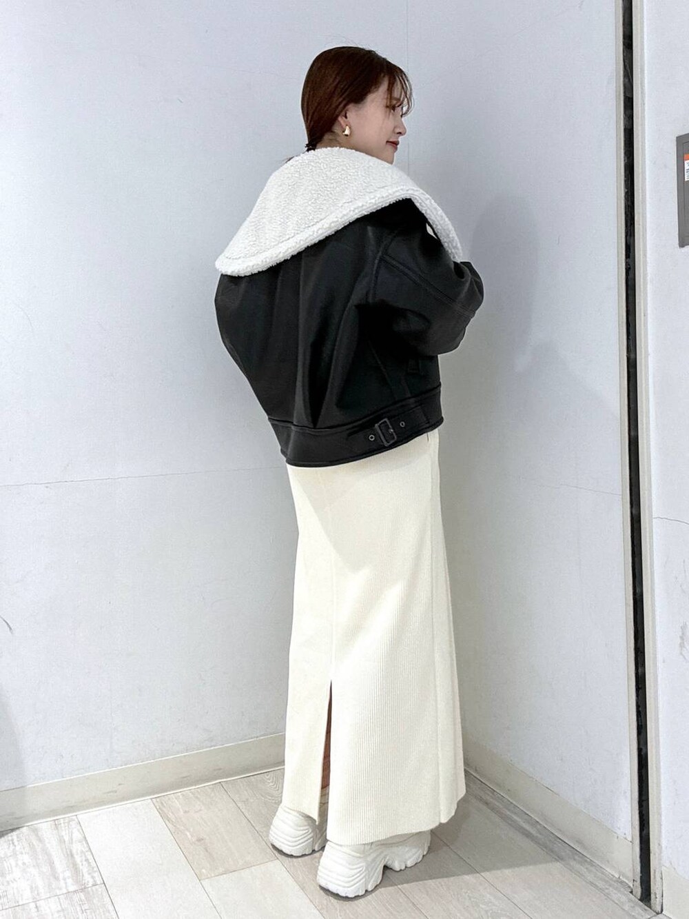 ホワイト系のスカート、ブラック系のブルゾン、ホワイト系のスニーカーを着用したレディースの冬コーディネートの2枚目の写真