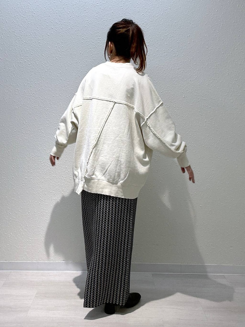 ブラック系のスカート、ホワイト系のスウェット、ブラック系のブーツを着用したレディースの秋コーディネートの3枚目の写真