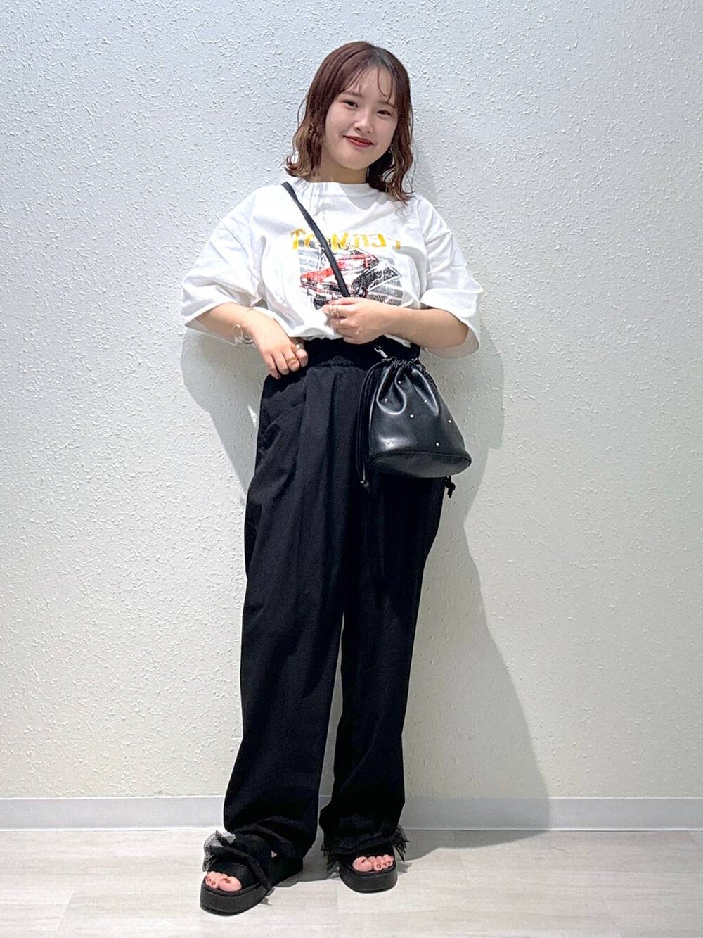 ブラック系のサンダル、ブラック系のショルダーバッグ、ホワイト系のTシャツ/カットソーを着用したレディースの夏コーディネートの2枚目の写真