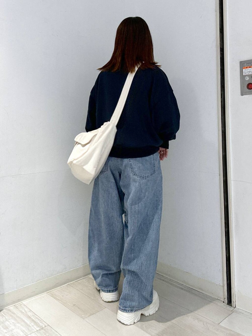 ブルー系のデニムパンツ、ホワイト系のスニーカー、ホワイト系のキャミソールを着用したレディースの秋コーディネートの3枚目の写真