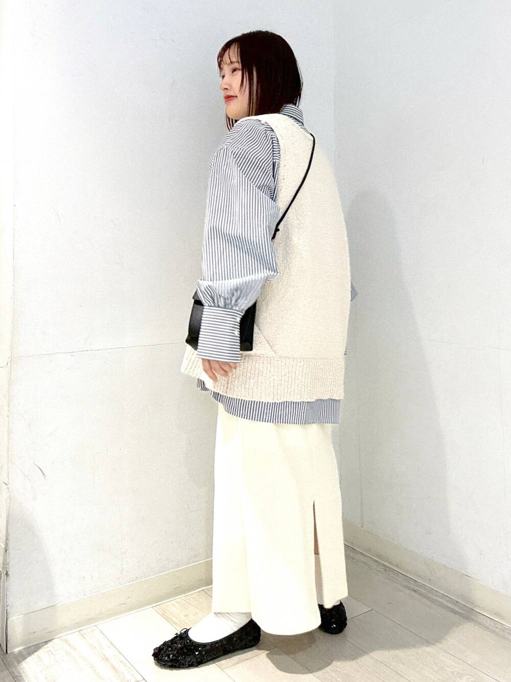 ホワイト系のスカート、ブラック系のショルダーバッグ、ブラック系のバレエシューズを着用したレディースの春コーディネートの2枚目の写真