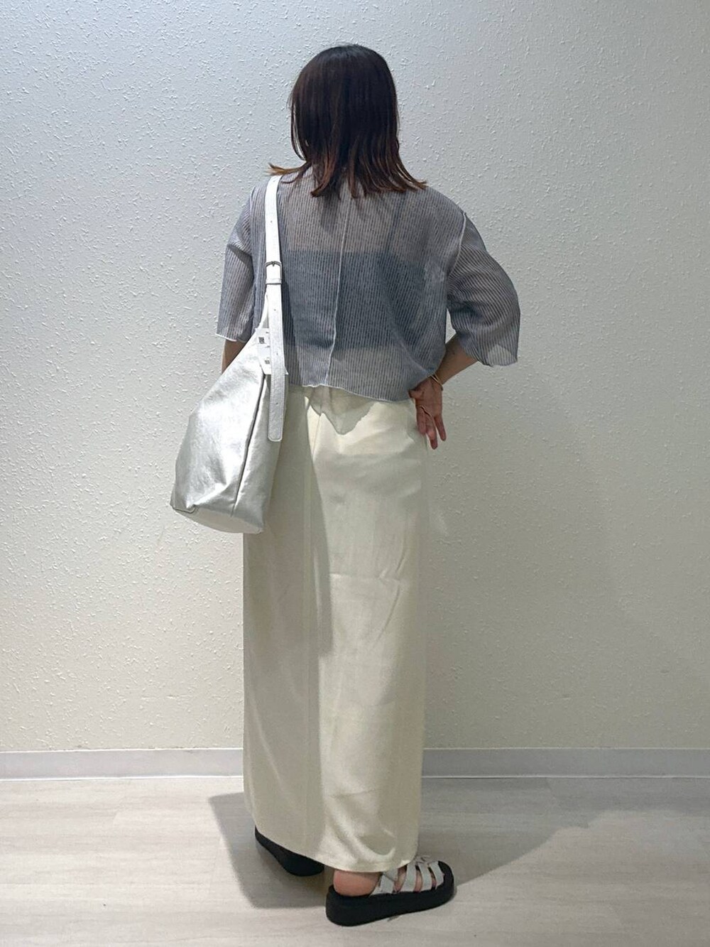 シルバー系のショルダーバッグ、シルバー系のスニーカー、グレー系のTシャツ/カットソーを着用したレディースの秋コーディネートの3枚目の写真