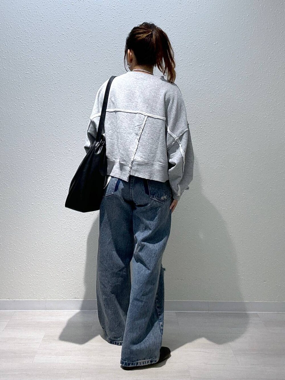 ブルー系のデニムパンツ、ブラック系のブーツ、グレー系のスウェットを着用したレディースの秋コーディネートの3枚目の写真