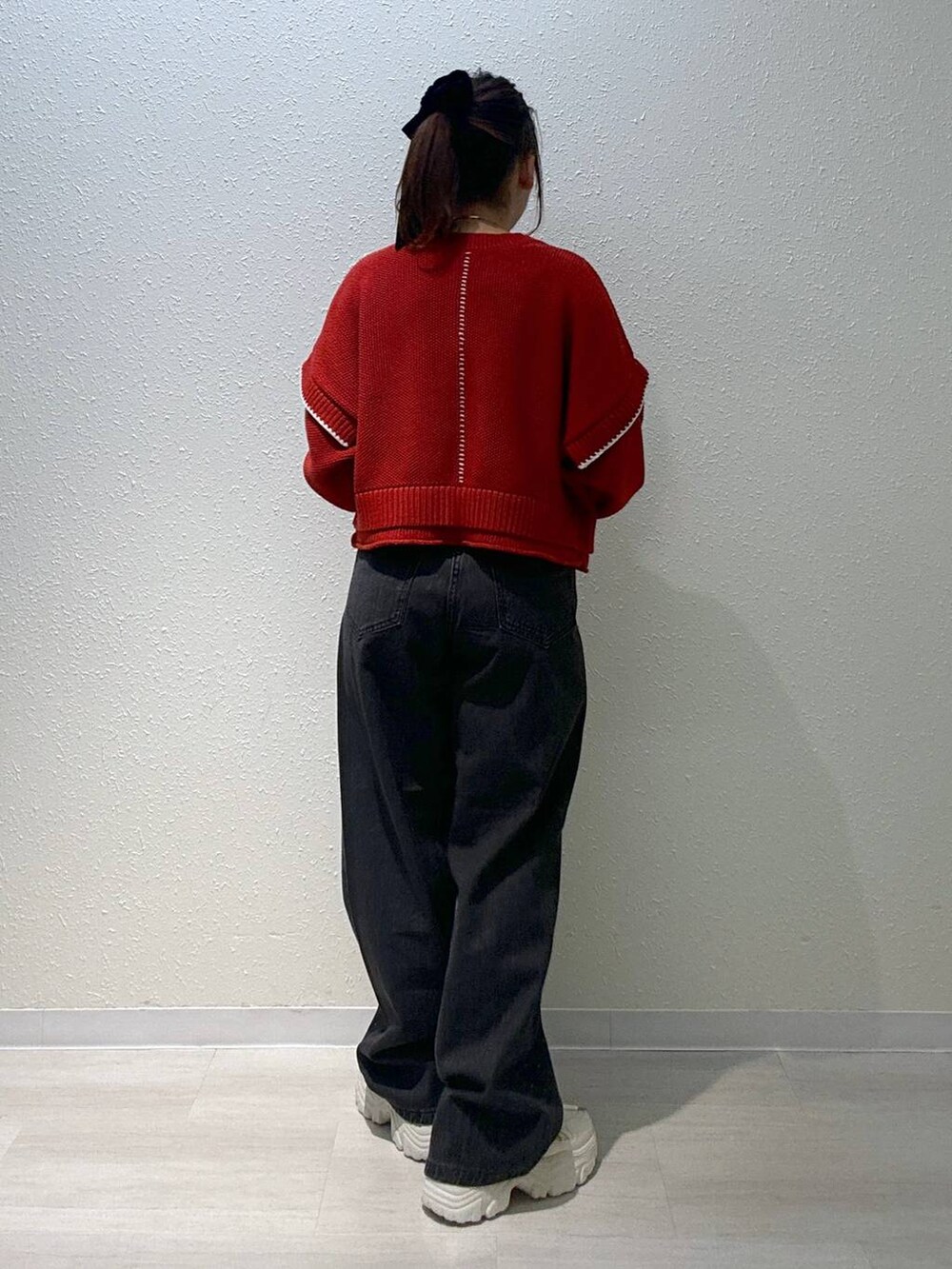 レッド系のニット/セーター、ホワイト系のスニーカー、ブラック系のデニムパンツを着用したレディースの秋コーディネートの4枚目の写真