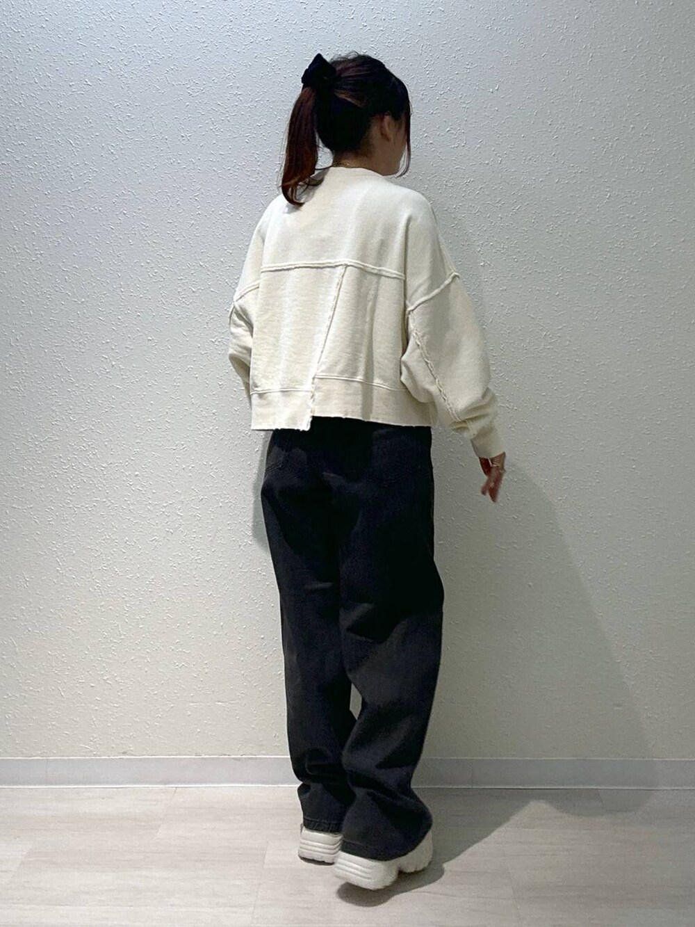 ホワイト系のスニーカー、ホワイト系のスウェット、ブラック系のデニムパンツを着用したレディースの秋コーディネートの5枚目の写真
