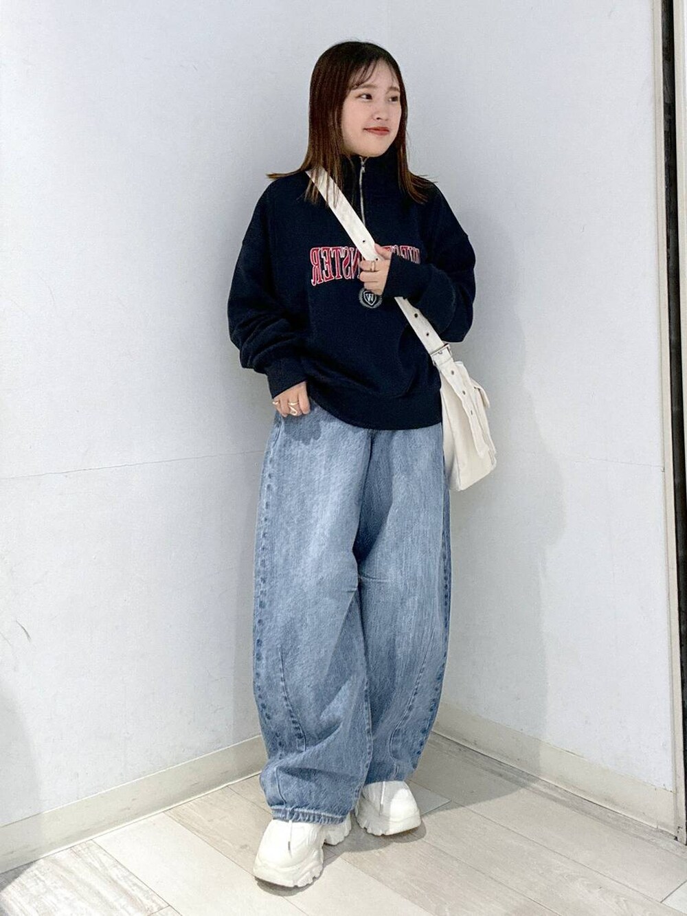 ブルー系のデニムパンツ、ホワイト系のスニーカー、ホワイト系のキャミソールを着用したレディースの秋コーディネートの2枚目の写真