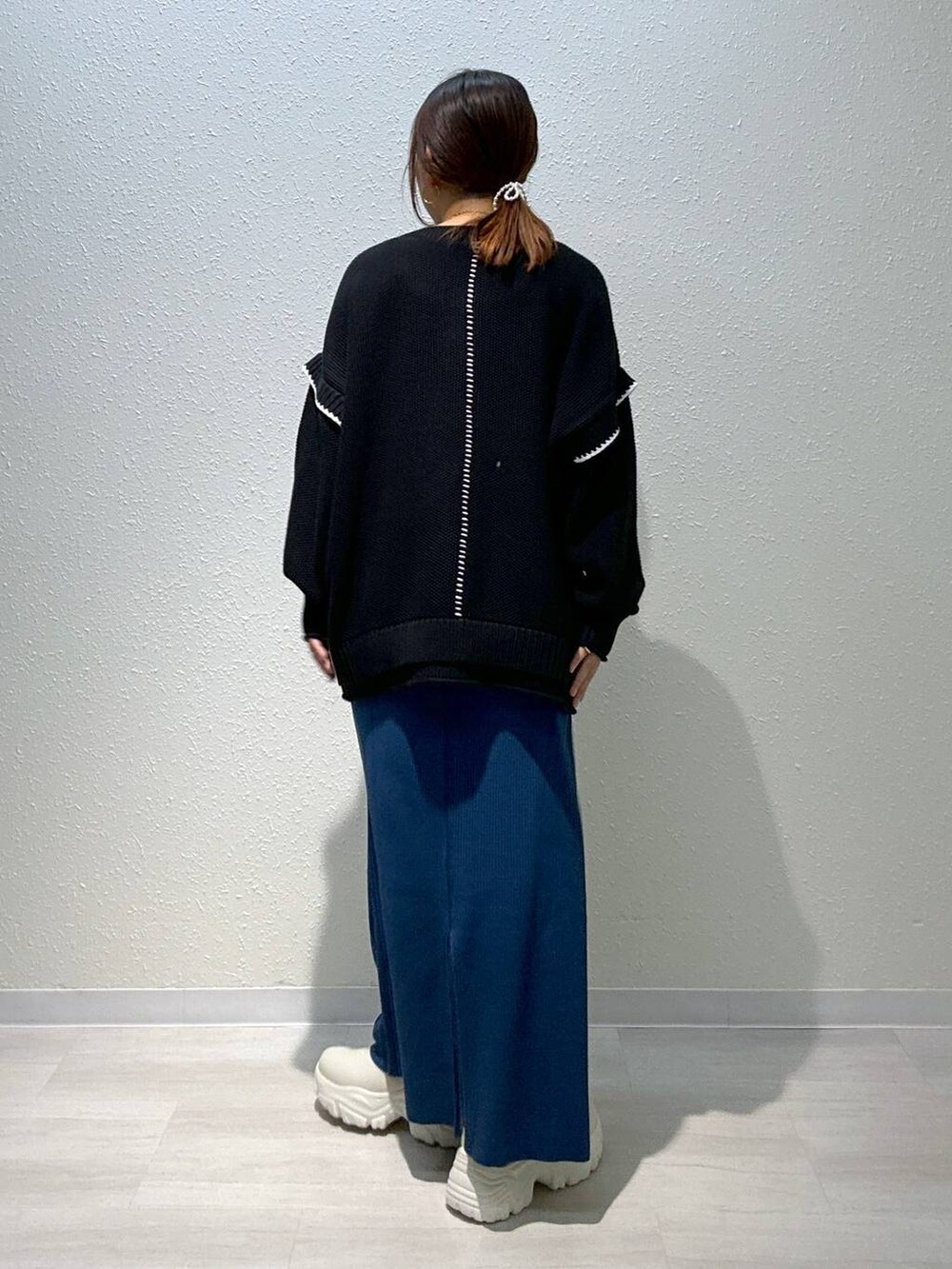 ブルー系のスカート、ブラック系のニット/セーター、ホワイト系のブーツを着用したレディースの秋コーディネートの3枚目の写真