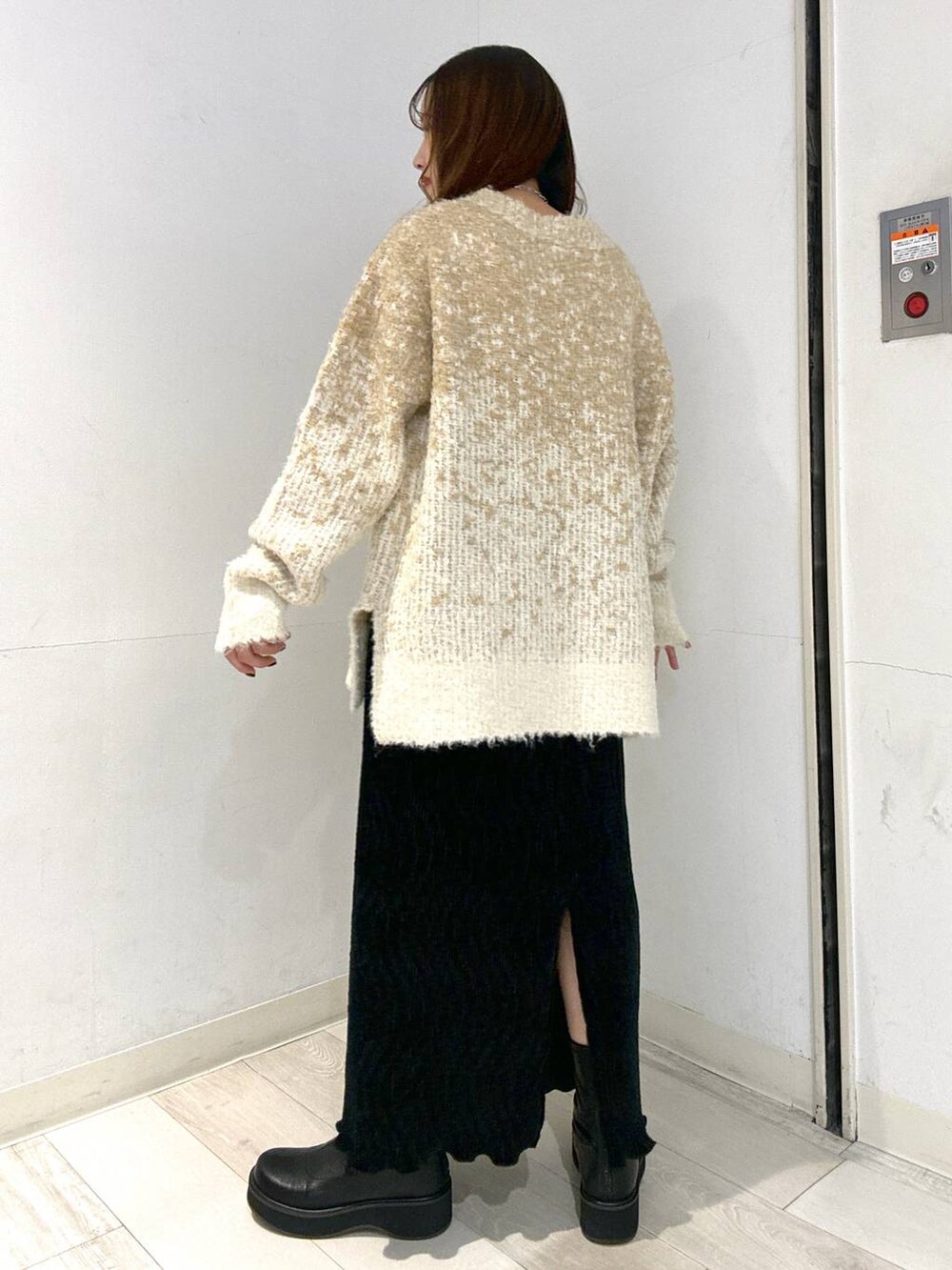 ブラック系のブーツ、ホワイト系のニット/セーター、ブラック系のスカートを着用したレディースの冬コーディネートの3枚目の写真