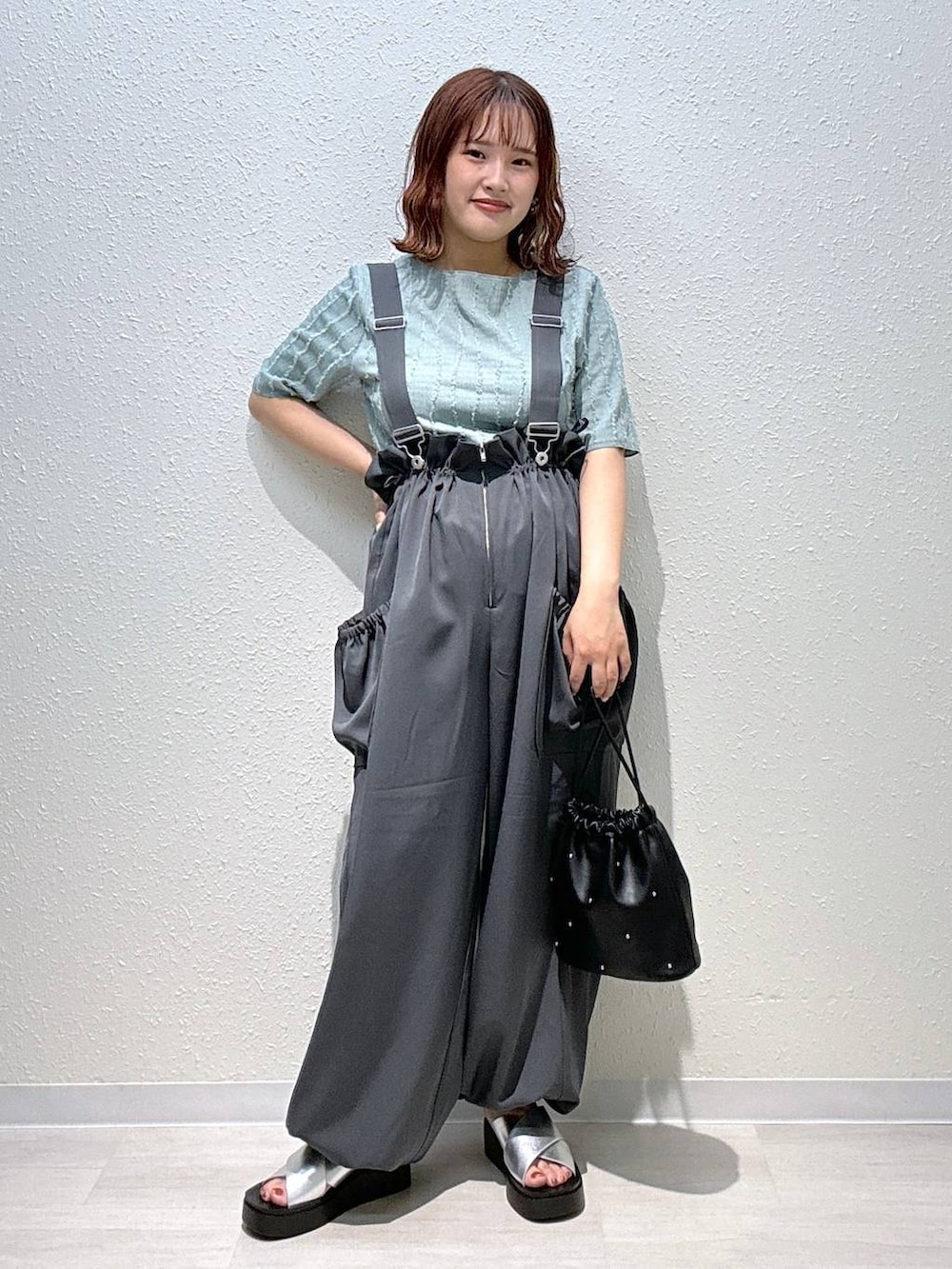 ブラック系のショルダーバッグ、シルバー系のサンダル、グリーン系のTシャツ/カットソーを着用したレディースの秋コーディネートの2枚目の写真
