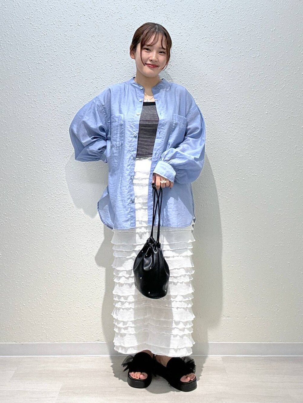 ブラック系のサンダル、ホワイト系のスカート、ブラック系のショルダーバッグを着用したレディースの夏コーディネートの2枚目の写真