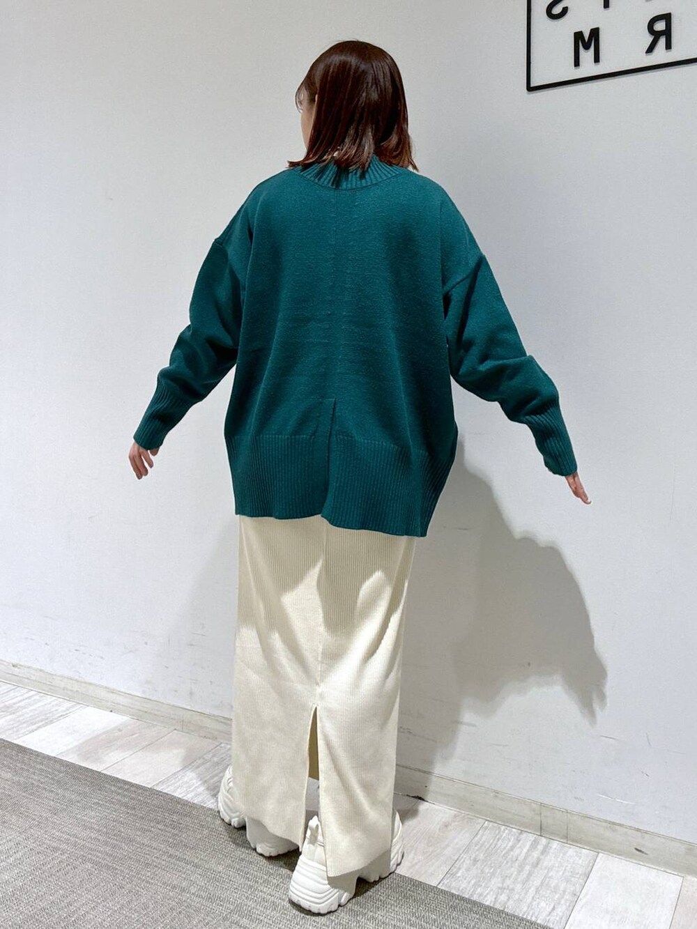 ホワイト系のスカート、ブラウン系のトレンチコート、グリーン系のニット/セーターを着用したレディースの冬コーディネートの4枚目の写真