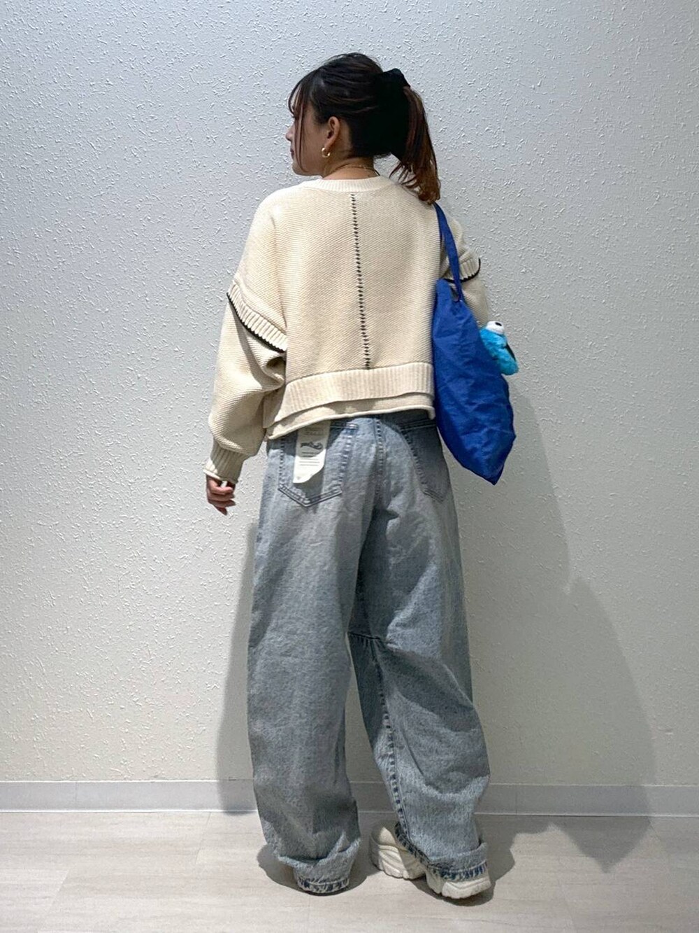 ホワイト系のニット/セーター、ブルー系のデニムパンツ、ホワイト系のブーツを着用したレディースの秋コーディネートの3枚目の写真