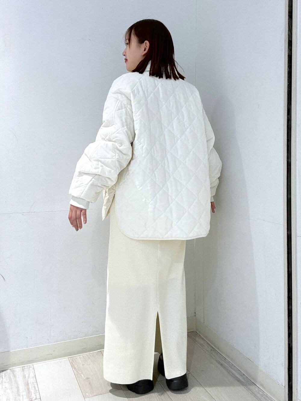 ホワイト系のスカート、ブラック系のブーツ、ホワイト系のブルゾンを着用したレディースの冬コーディネートの2枚目の写真