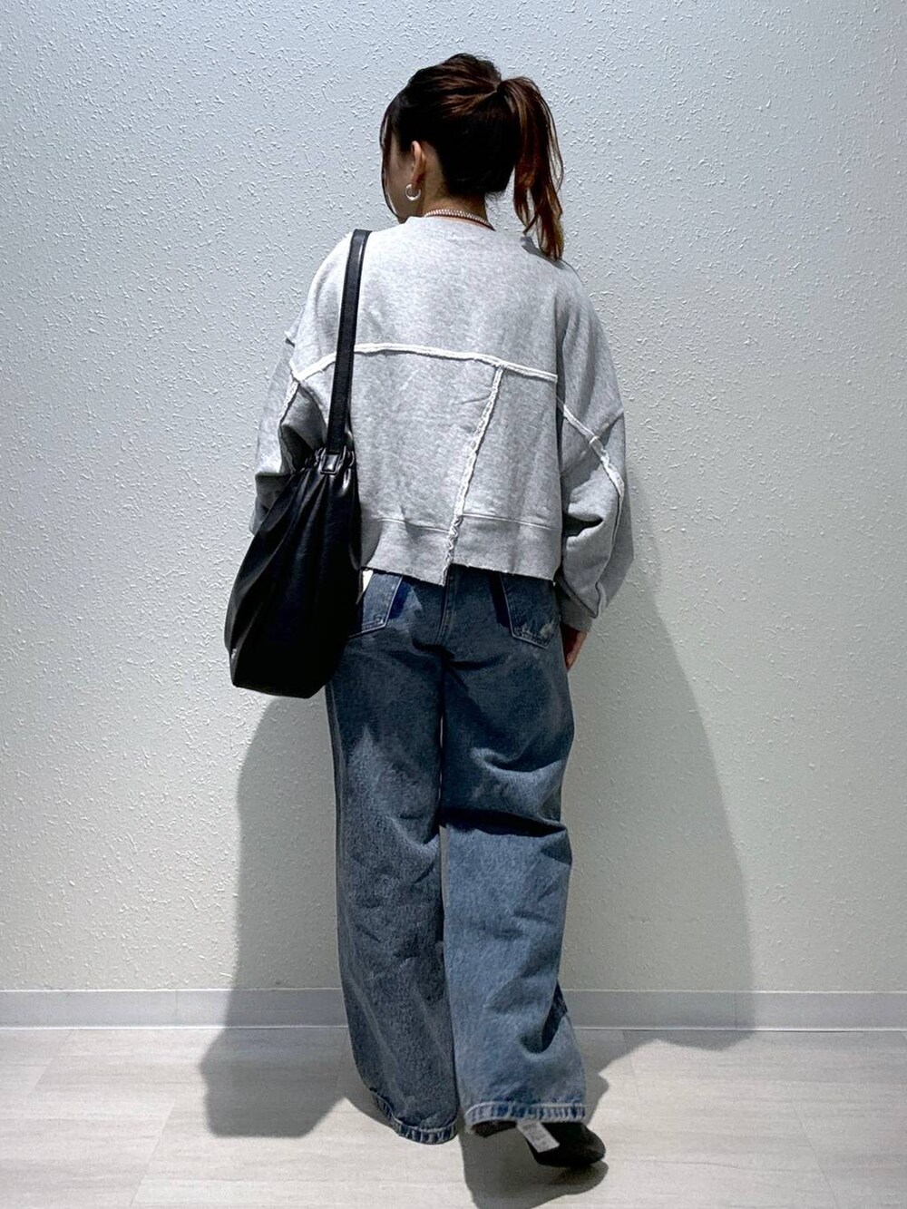 ブルー系のデニムパンツ、ブラック系のブーツ、グレー系のスウェットを着用したレディースの秋コーディネートの4枚目の写真