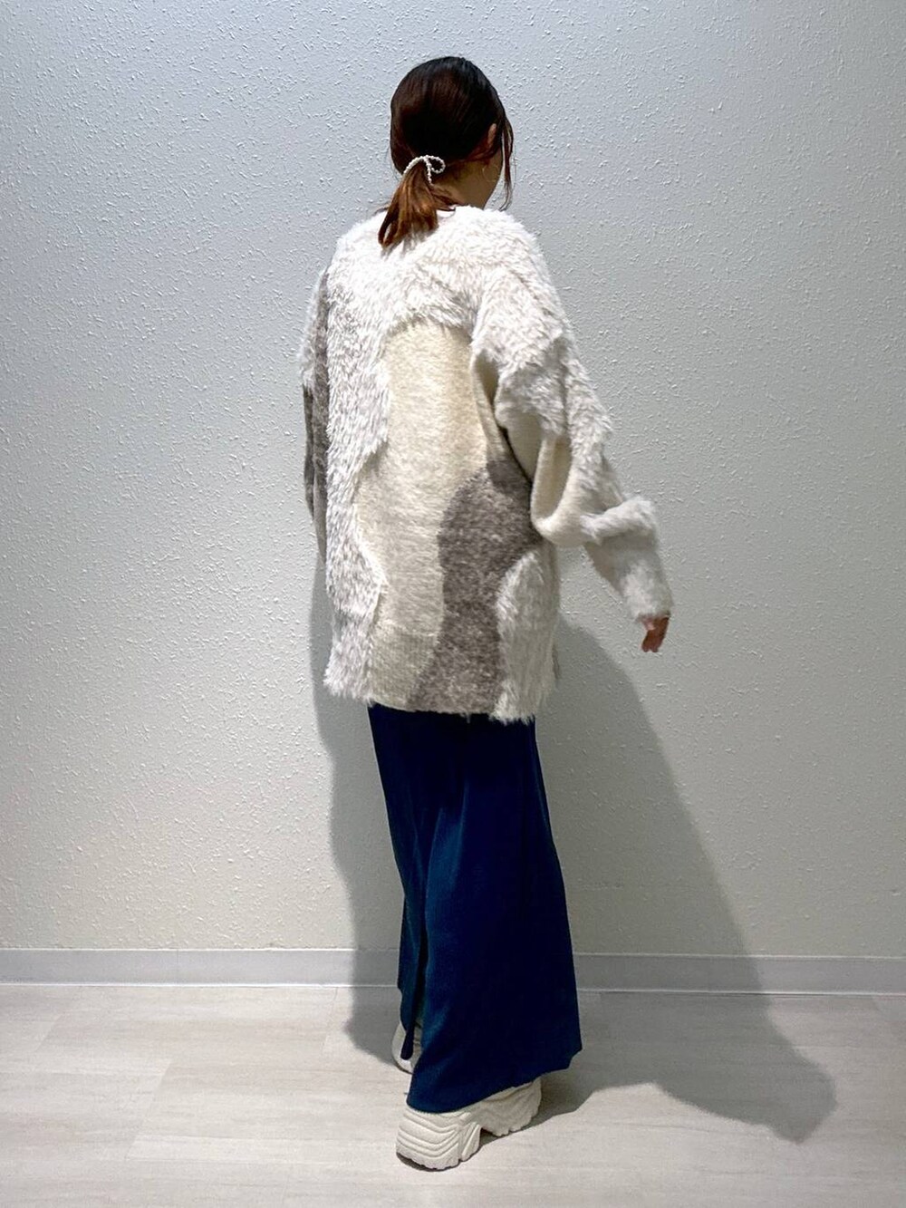 ブルー系のスカート、ホワイト系のカーディガン/ボレロ、ホワイト系のブーツを着用したレディースの秋コーディネートの3枚目の写真