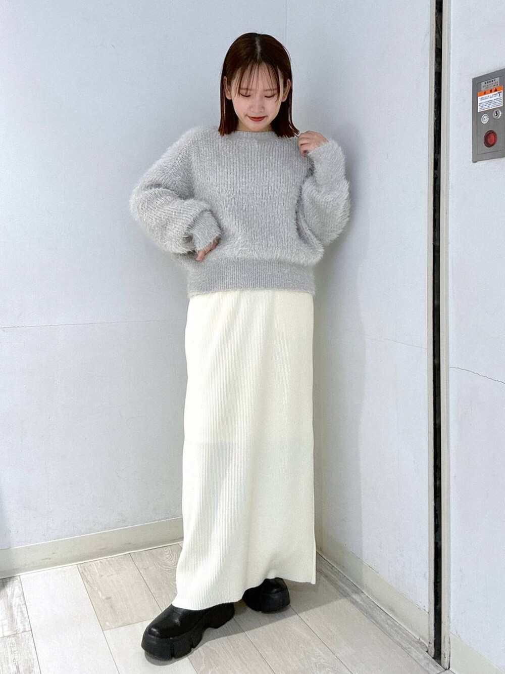 ホワイト系のスカート、ブラック系のブーツ、ホワイト系のブルゾンを着用したレディースの冬コーディネートの3枚目の写真