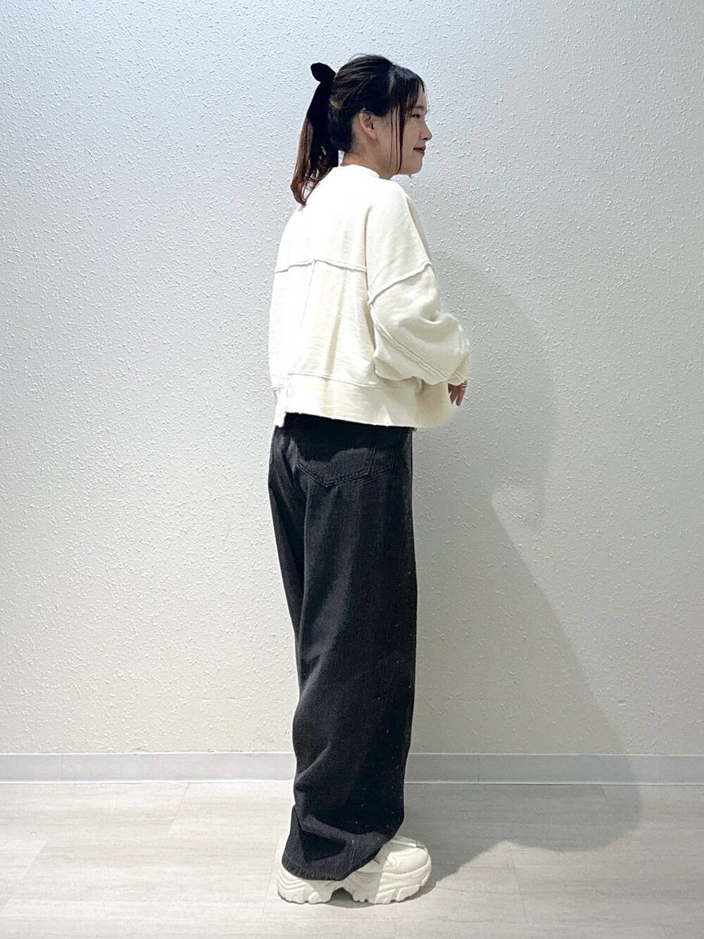 ホワイト系のスニーカー、ホワイト系のスウェット、ブラック系のデニムパンツを着用したレディースの秋コーディネートの3枚目の写真