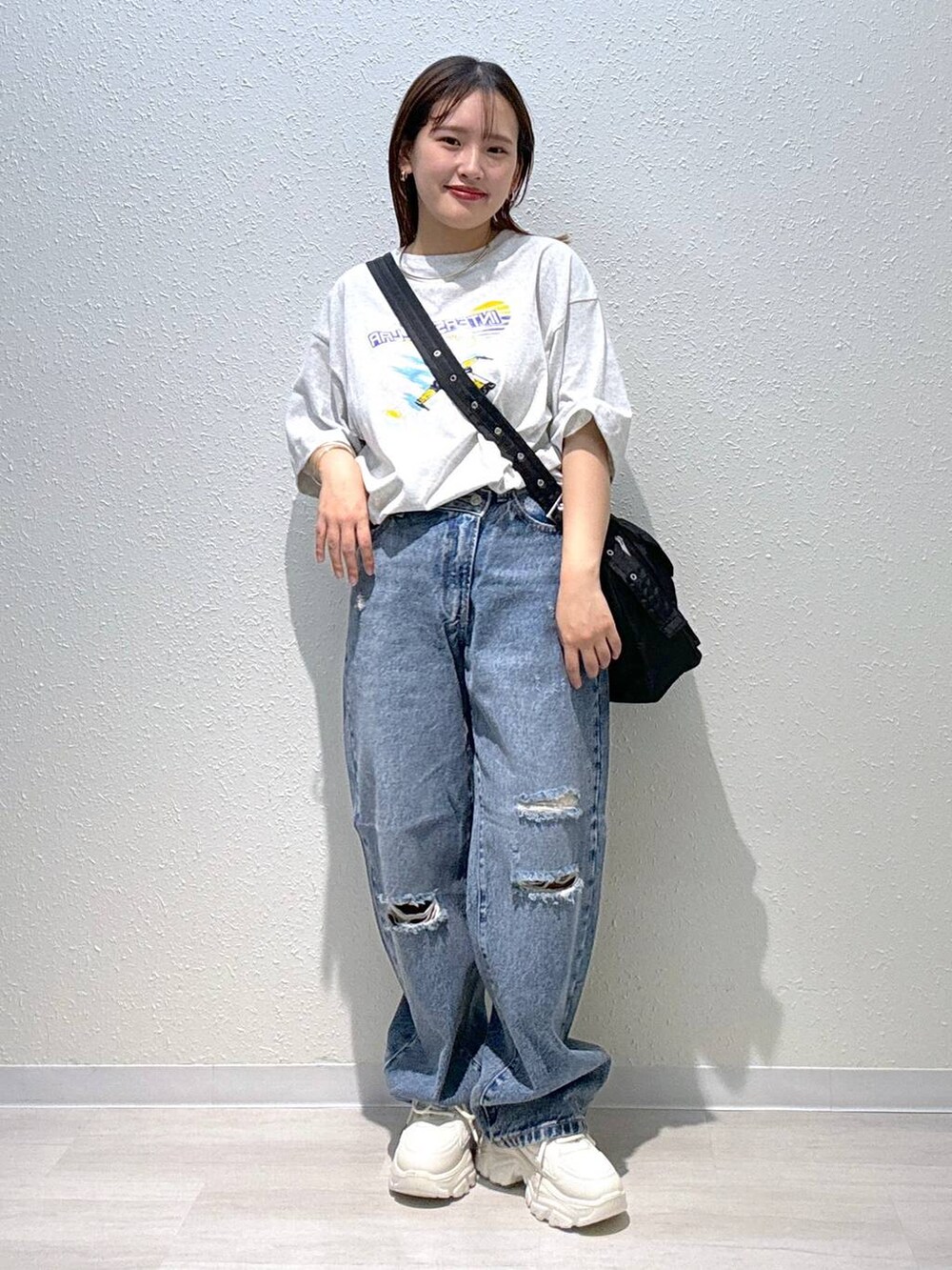 ホワイト系のスニーカー、ブラック系のショルダーバッグ、ブルー系のデニムパンツを着用したレディースの秋コーディネートの2枚目の写真