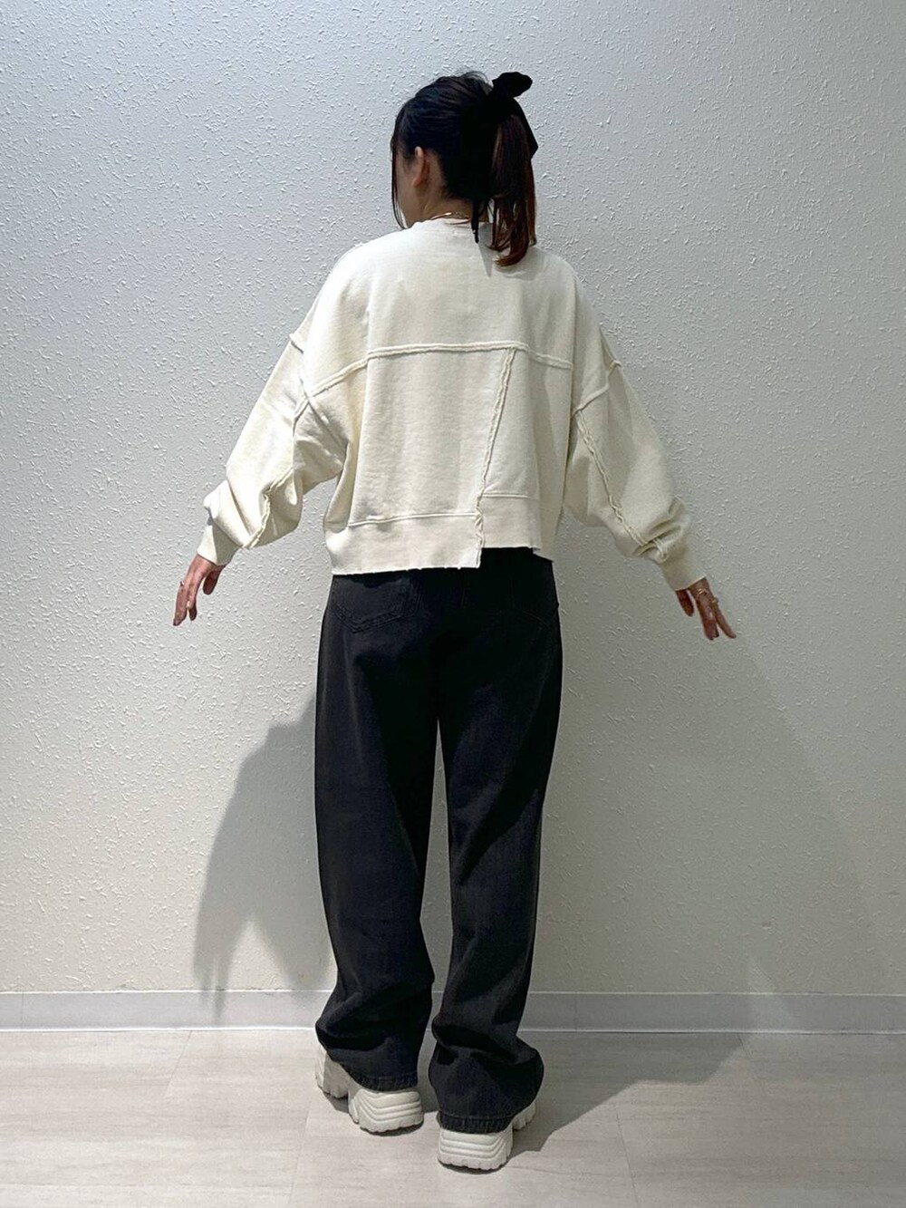 ホワイト系のスニーカー、ホワイト系のスウェット、ブラック系のデニムパンツを着用したレディースの秋コーディネートの6枚目の写真