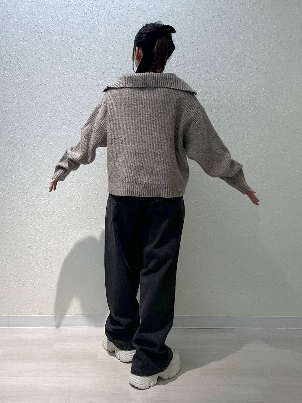 ブラック系のデニムパンツ、ホワイト系のスニーカー、ホワイト系のキャミソールを着用したレディースの秋コーディネートの3枚目の写真