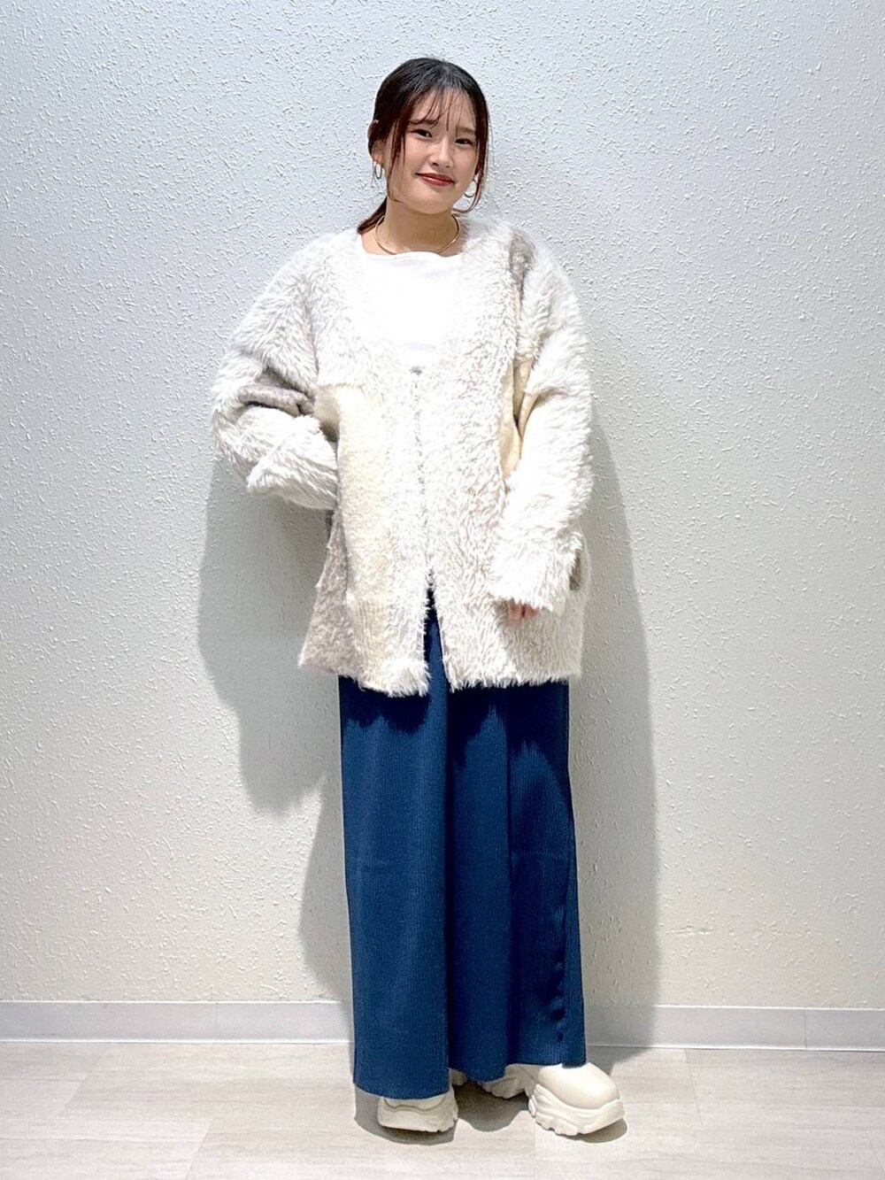 ブルー系のスカート、ホワイト系のカーディガン/ボレロ、ホワイト系のブーツを着用したレディースの秋コーディネートの2枚目の写真