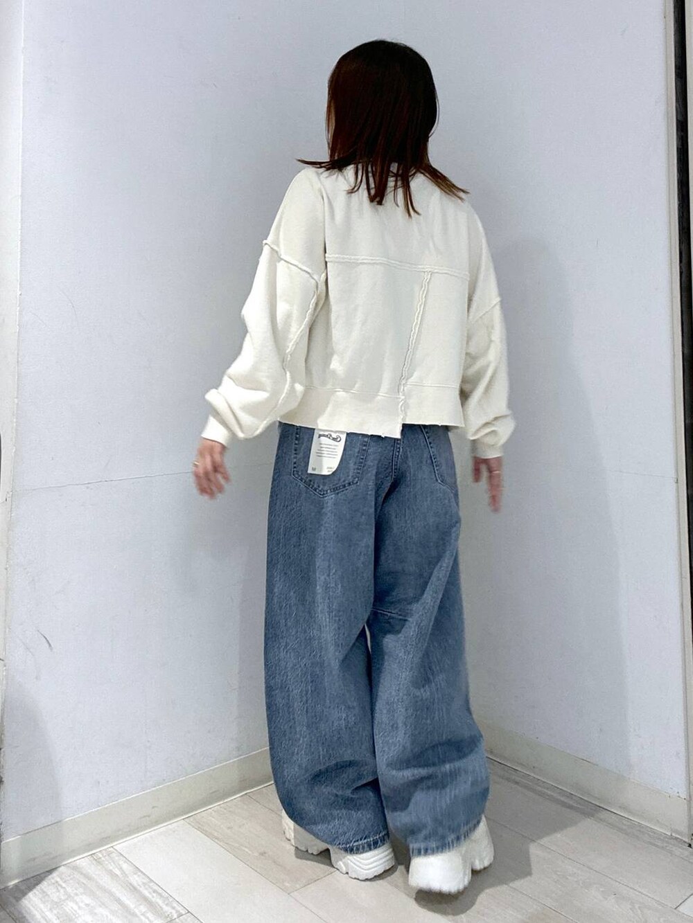 ホワイト系のスニーカー、ブルー系のデニムパンツ、ホワイト系のスウェットを着用したレディースの秋コーディネートの4枚目の写真