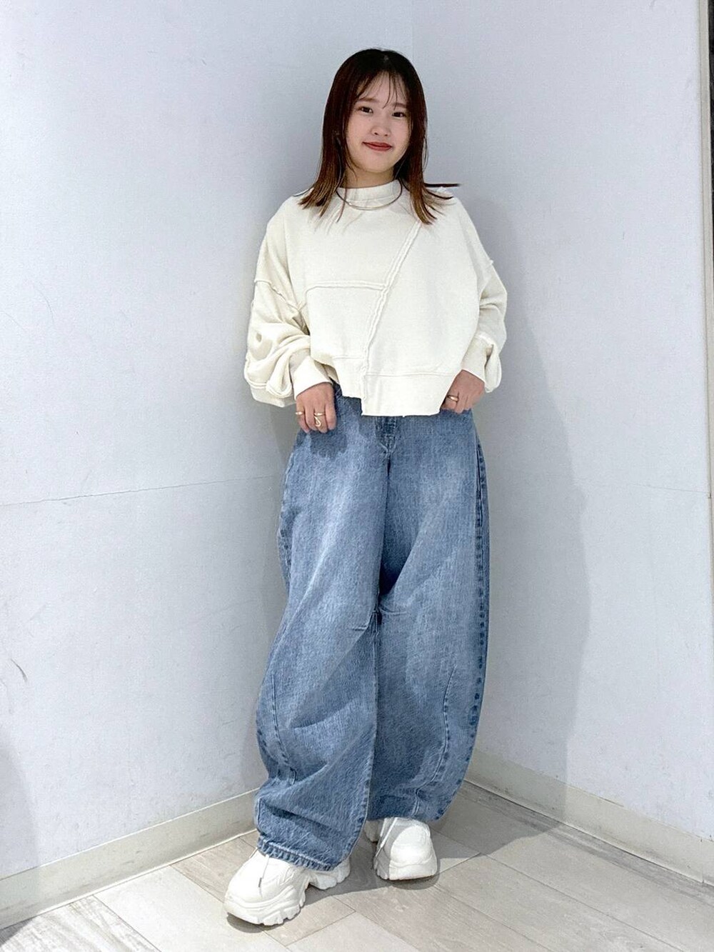 ホワイト系のスニーカー、ブルー系のデニムパンツ、ホワイト系のスウェットを着用したレディースの秋コーディネートの2枚目の写真