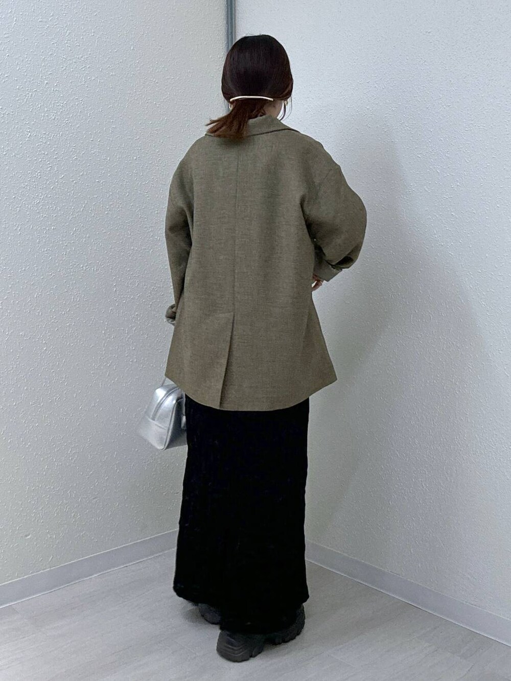 ブラウン系のテーラードジャケット、ブラック系のブーツ、ブラック系のキャミソールを着用したレディースの秋コーディネートの2枚目の写真