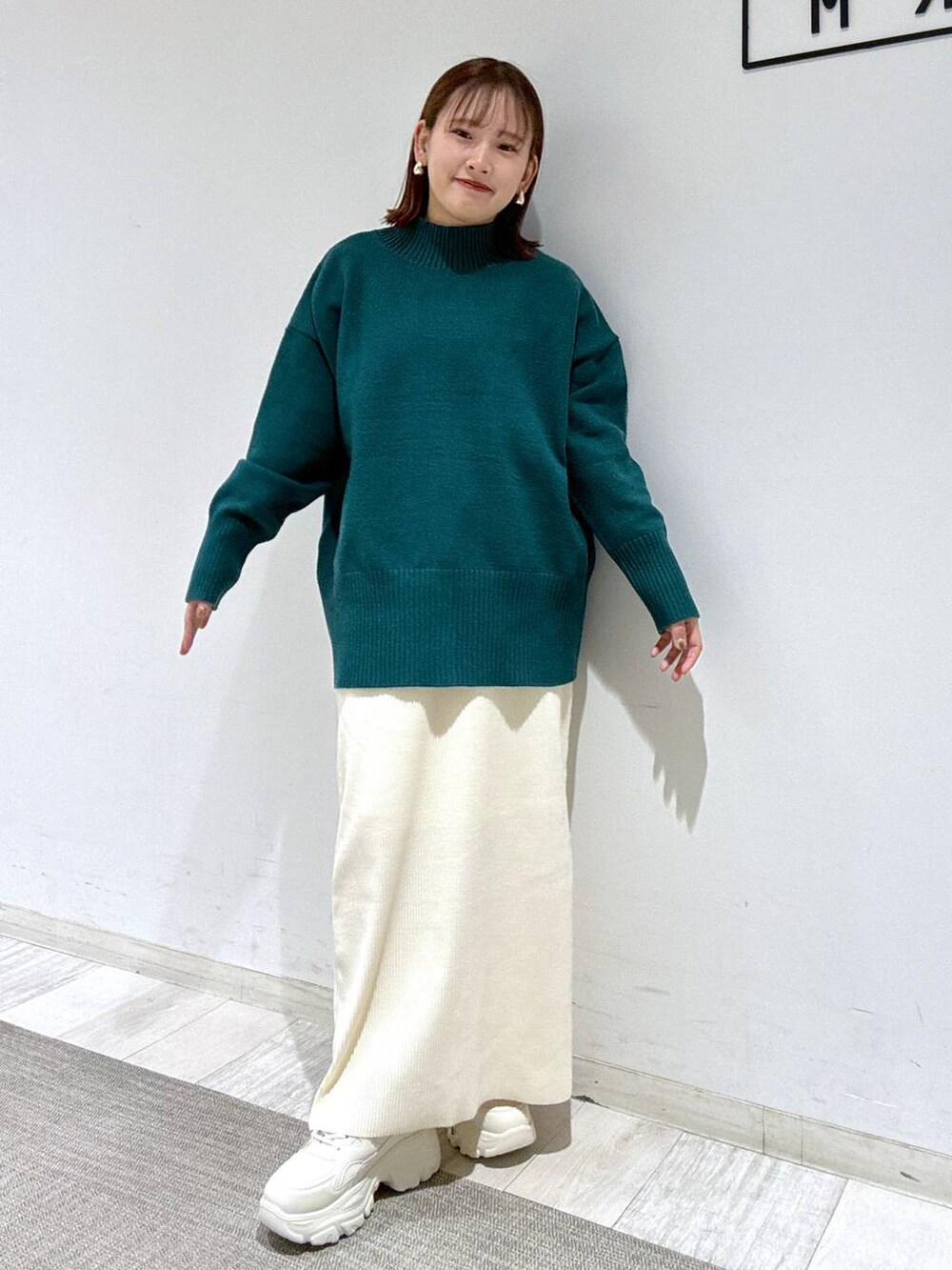 ホワイト系のスカート、ブラウン系のトレンチコート、グリーン系のニット/セーターを着用したレディースの冬コーディネートの3枚目の写真