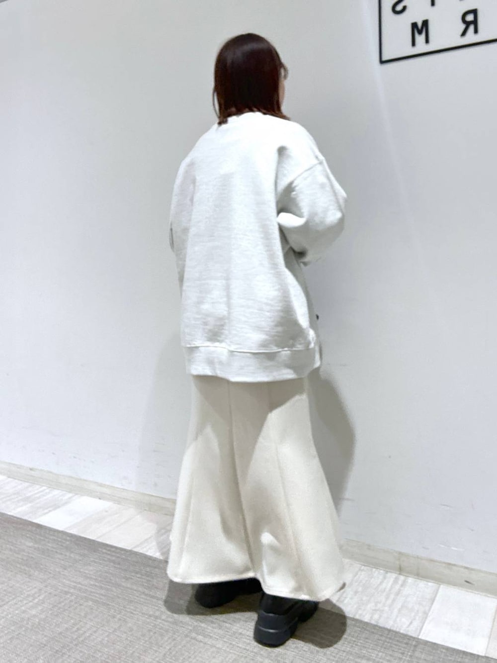 ブラック系のTシャツ/カットソー、ブラック系のブーツ、ホワイト系のスカートを着用したレディースの冬コーディネートの2枚目の写真