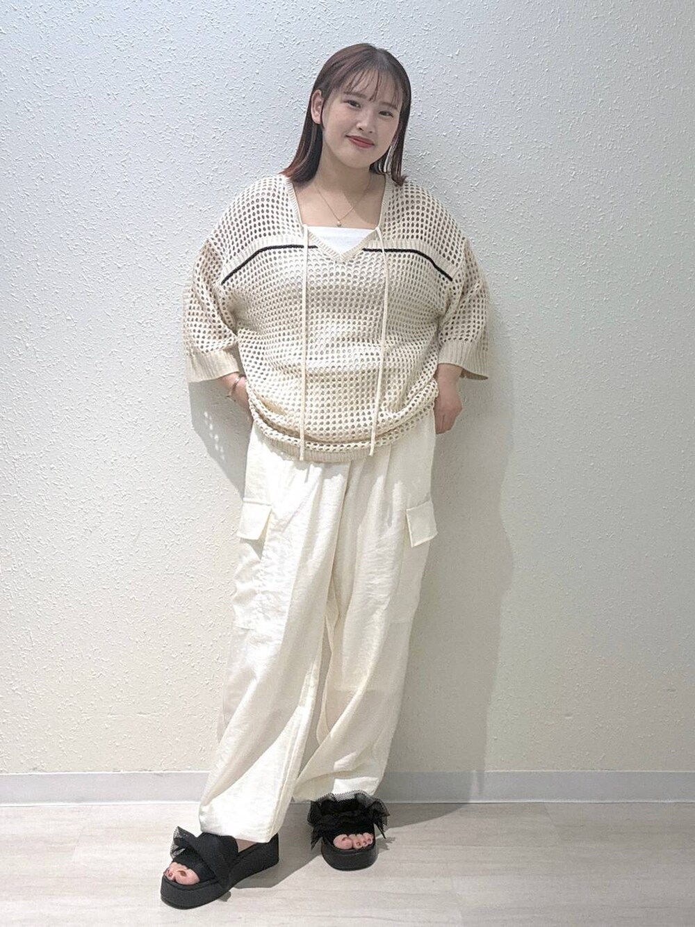 ブラック系のサンダル、ホワイト系のカーゴパンツ、ホワイト系のニット/セーターを着用したレディースの夏コーディネートの2枚目の写真