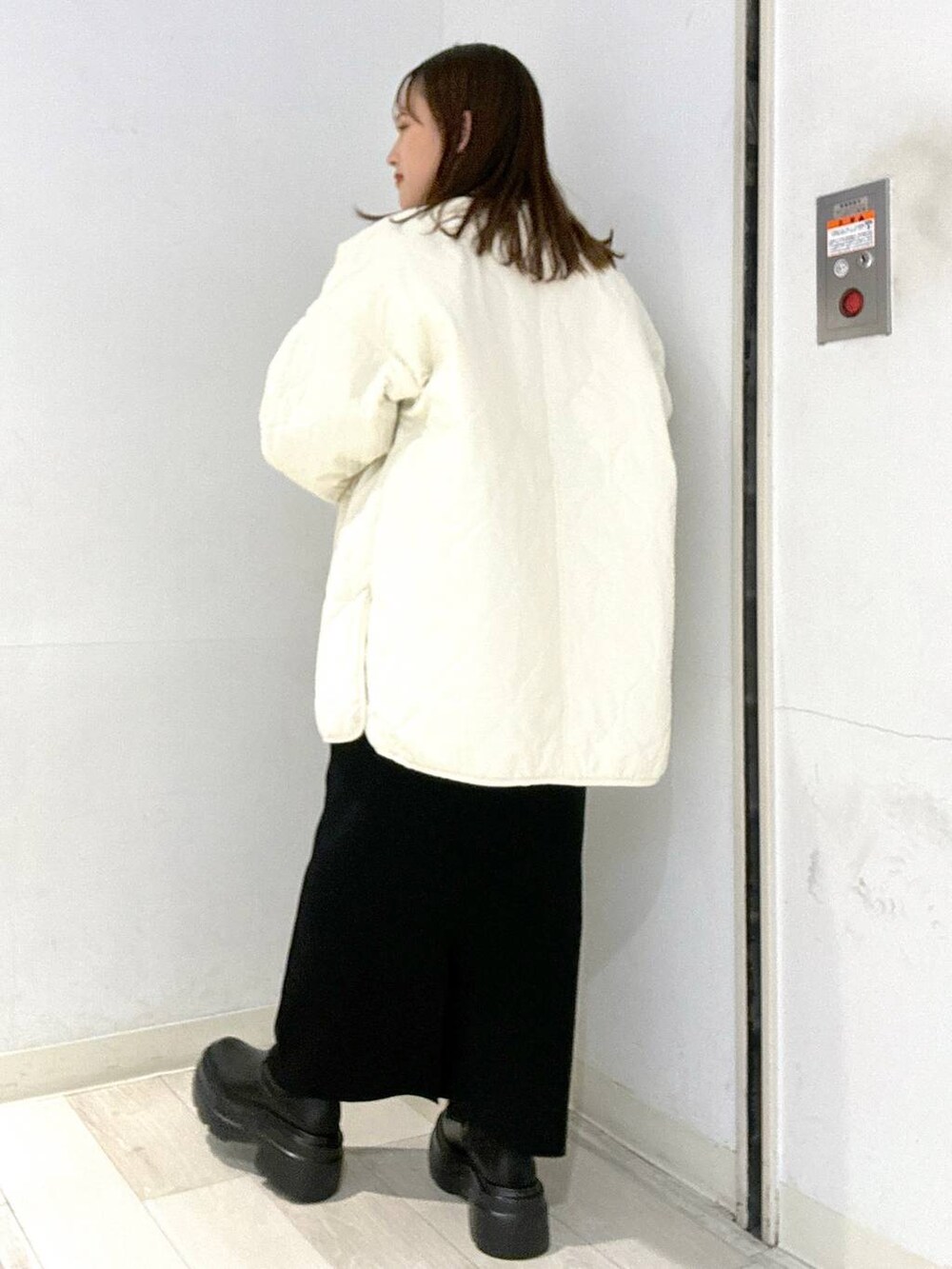 ホワイト系のブルゾン、ブラック系のブーツ、ブラック系のスカートを着用したレディースの秋コーディネートの3枚目の写真