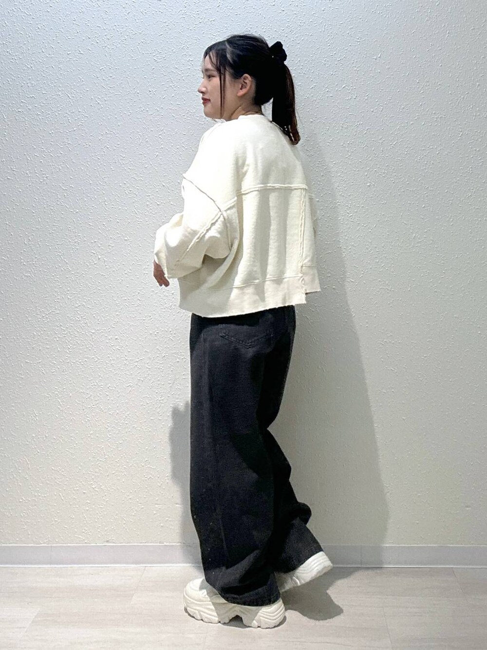 ホワイト系のスニーカー、ホワイト系のスウェット、ブラック系のデニムパンツを着用したレディースの秋コーディネートの4枚目の写真