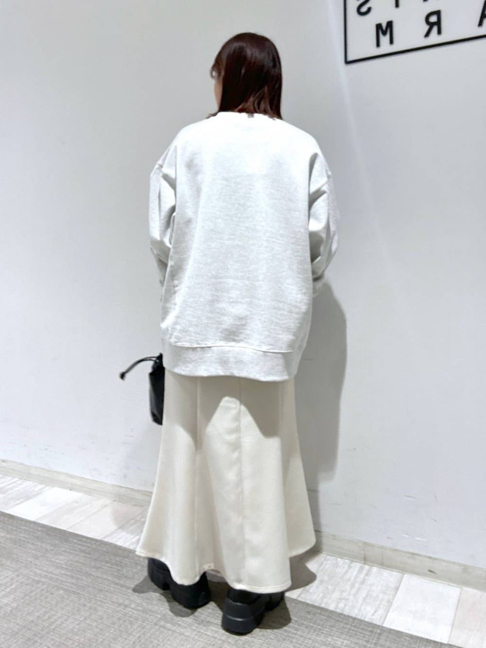 ブラック系のTシャツ/カットソー、ブラック系のブーツ、ホワイト系のスカートを着用したレディースの冬コーディネートの3枚目の写真