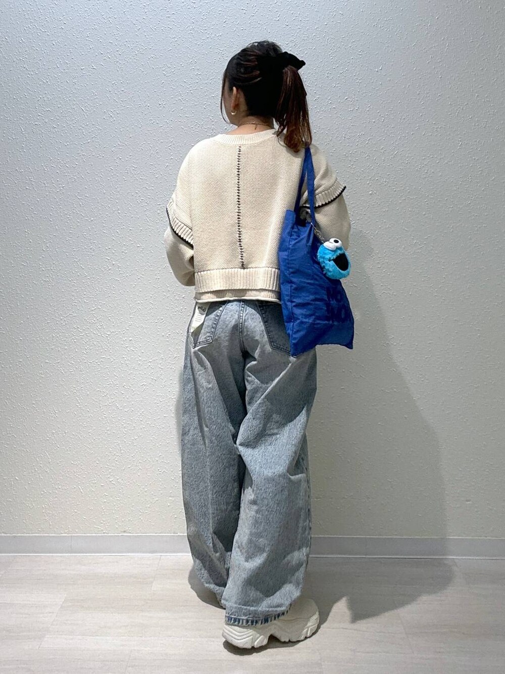 ホワイト系のニット/セーター、ブルー系のデニムパンツ、ホワイト系のブーツを着用したレディースの秋コーディネートの2枚目の写真