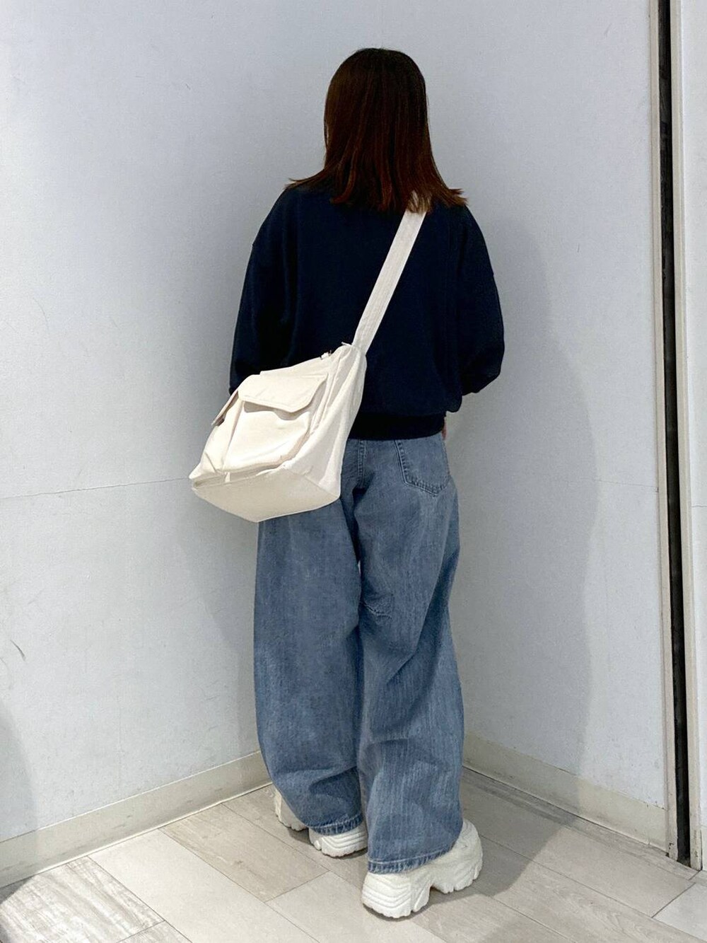 ブルー系のデニムパンツ、ホワイト系のスニーカー、ホワイト系のキャミソールを着用したレディースの秋コーディネートの4枚目の写真