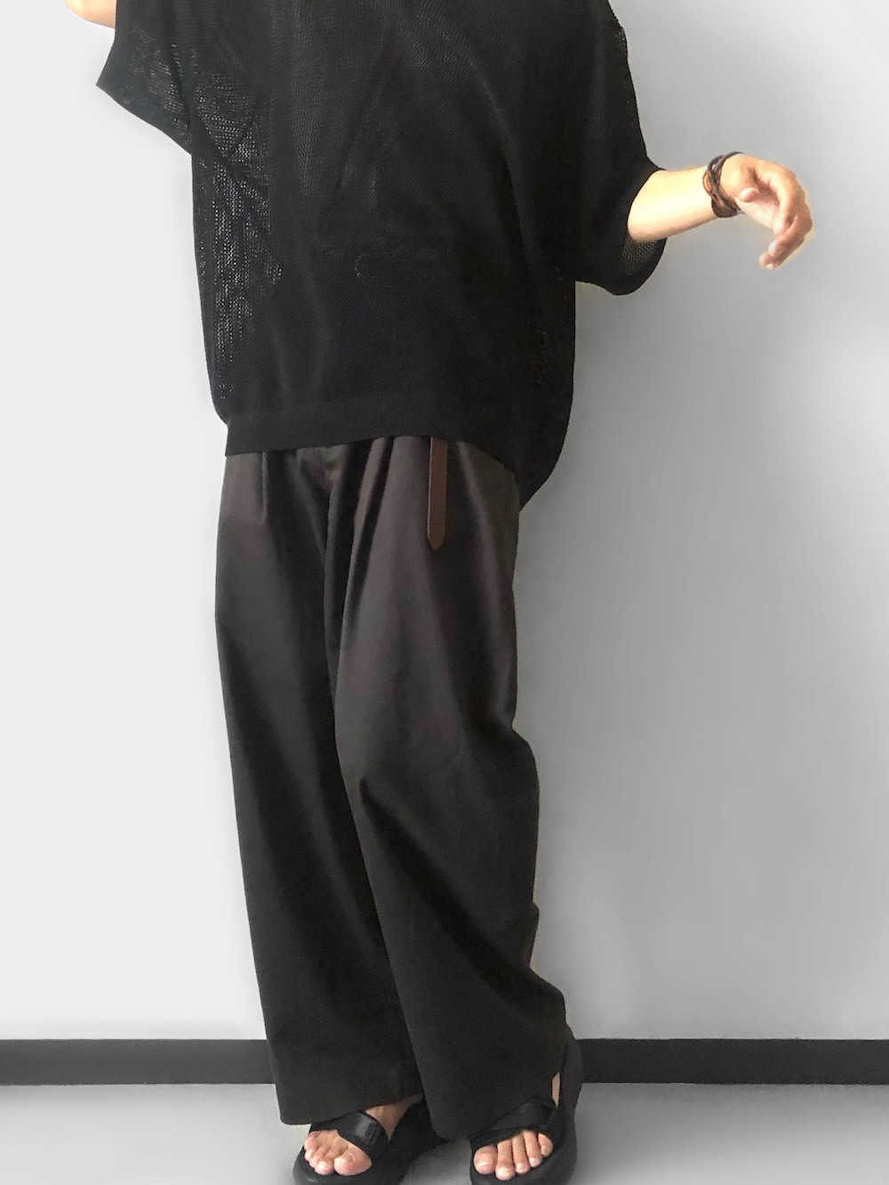 ブラック系のポロシャツ、グレー系のその他パンツ、ブラック系のサンダルを着用したメンズの夏コーディネートの2枚目の写真