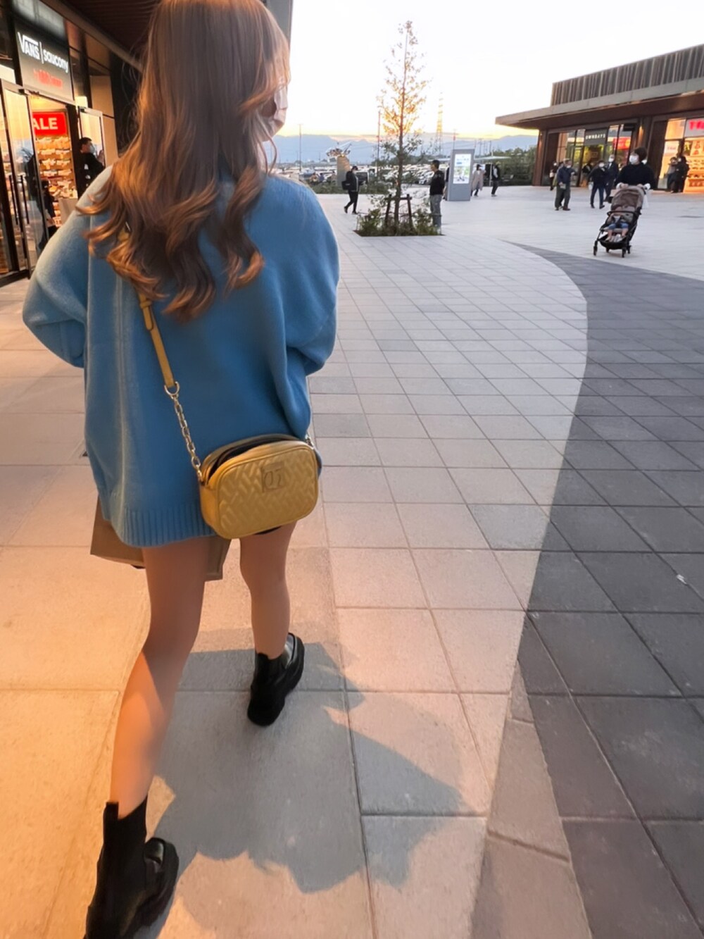 ブルー系のニット/セーター、イエロー系のショルダーバッグ、ブラック系のブーツを着用したレディースの秋コーディネートの2枚目の写真