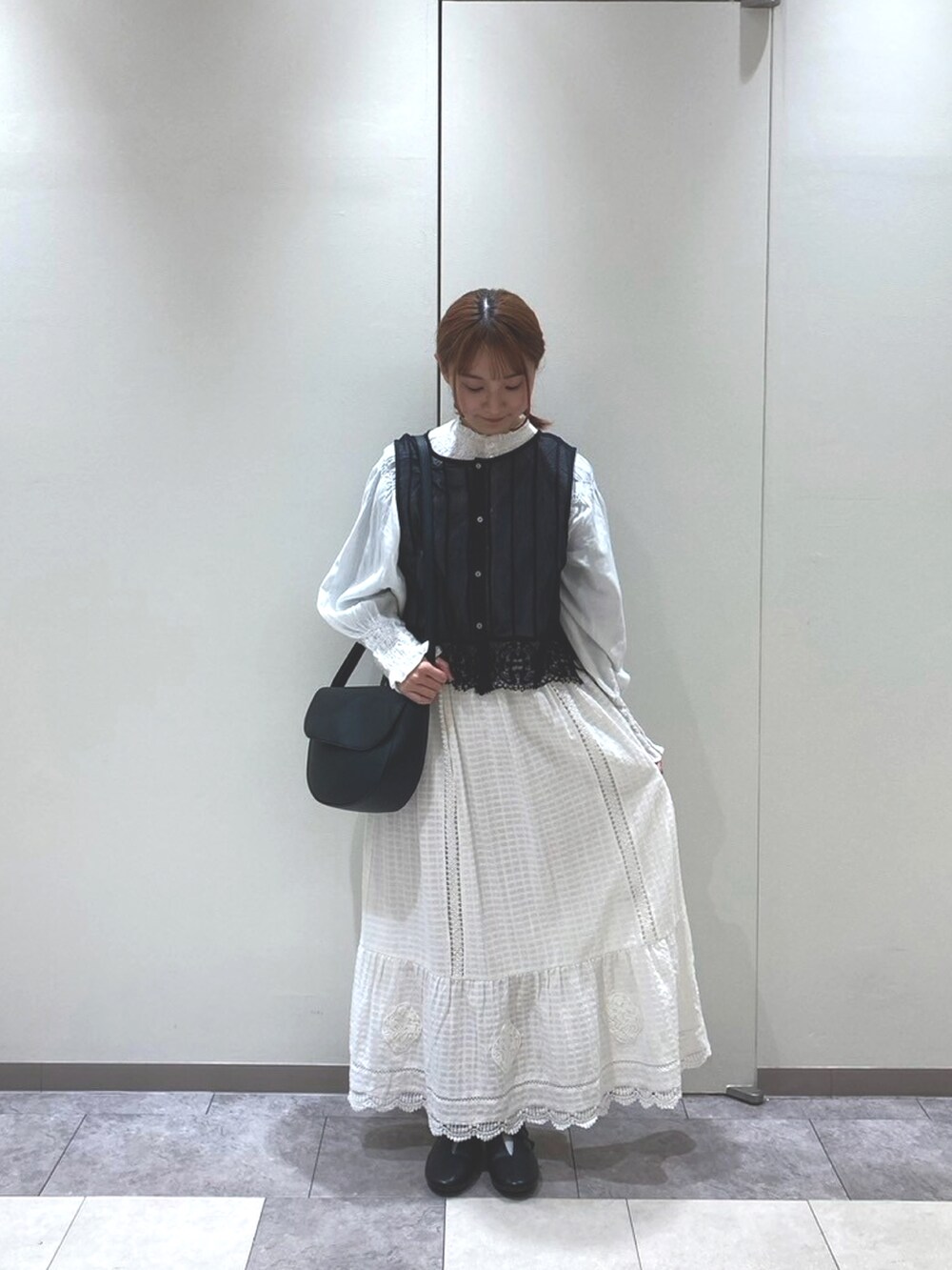 ブラック系のベスト、ホワイト系のシャツ/ブラウス、ホワイト系のスカートを着用したレディースの春コーディネートの2枚目の写真