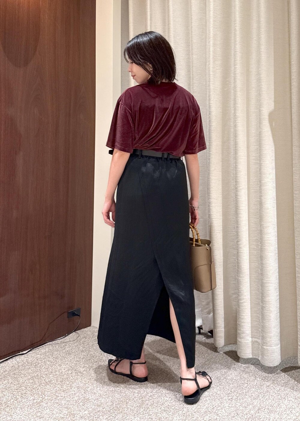 ブラック系のスカート、レッド系のTシャツ/カットソー、ベージュ系のハンドバッグを着用したレディースの夏コーディネートの3枚目の写真