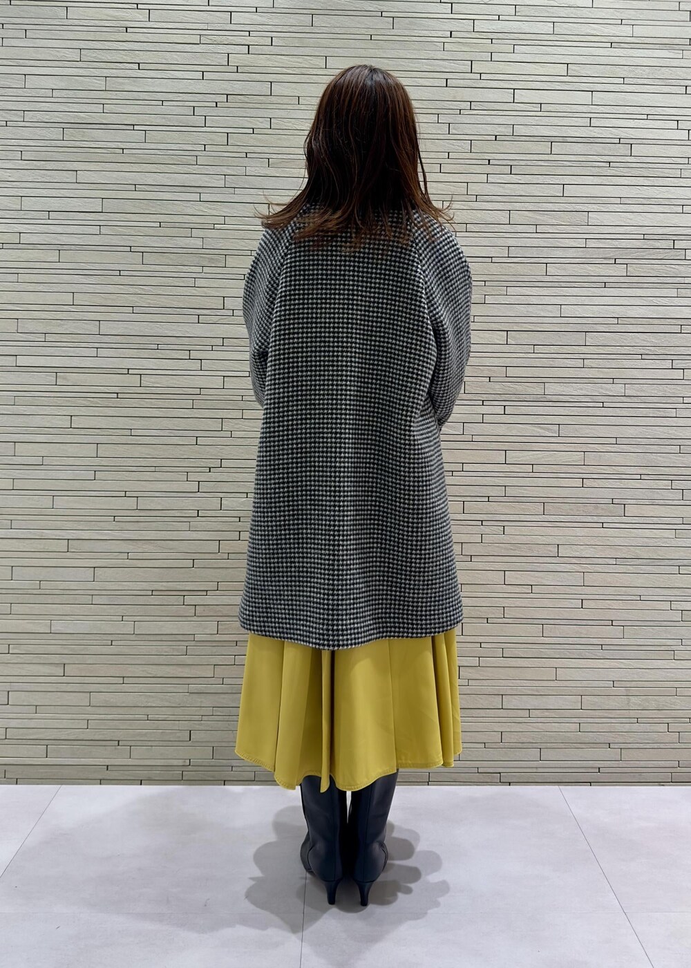 ブラック系のブーツ、ブラック系のその他アウター、イエロー系のハンドバッグを着用したレディースの冬コーディネートの3枚目の写真