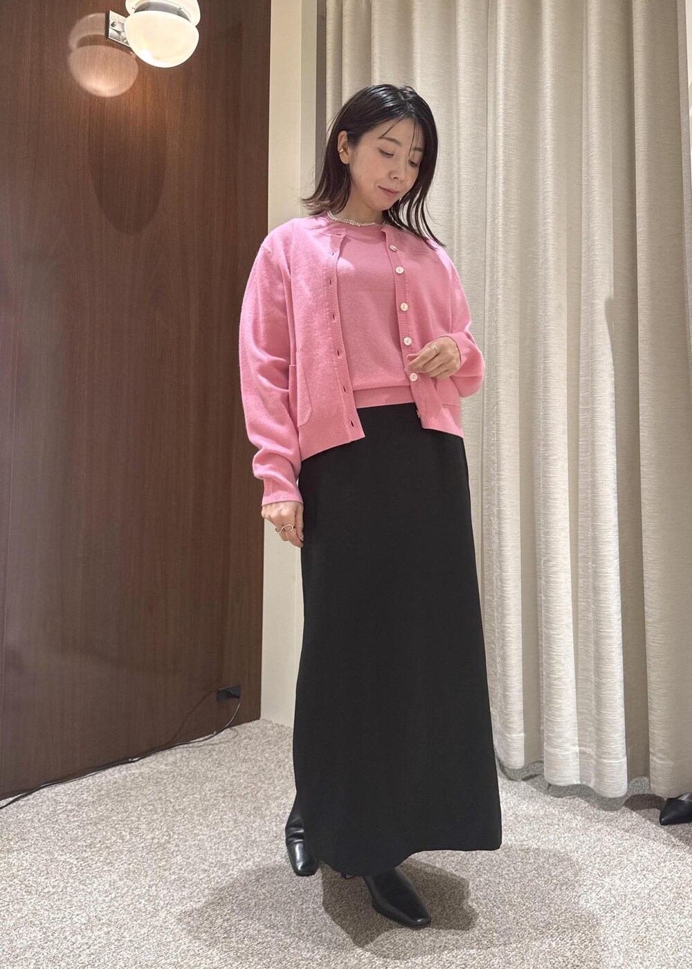 ブラック系のスカート、ベージュ系のハンドバッグ、ブラック系のブーツを着用したレディースの秋コーディネートの7枚目の写真