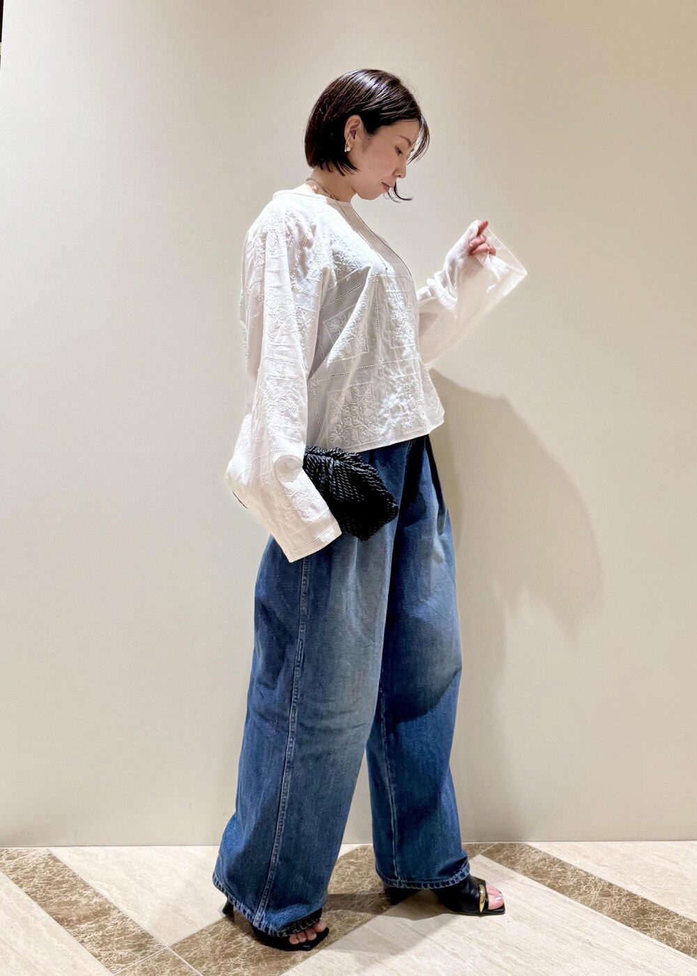 ブルー系のデニムパンツ、ブラック系のサンダル、ホワイト系のシャツ/ブラウスを着用したレディースの春コーディネートの2枚目の写真