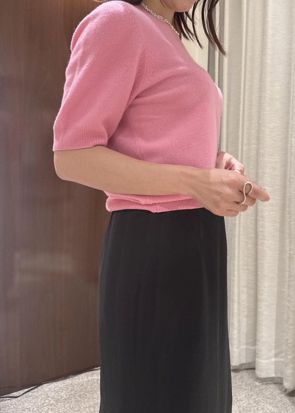 ブラック系のスカート、ベージュ系のハンドバッグ、ブラック系のブーツを着用したレディースの秋コーディネートの6枚目の写真