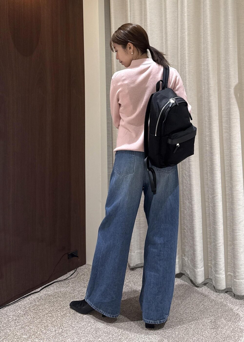 ブルー系のデニムパンツ、ブラック系のブーツ、ブラック系のバックパック/リュックを着用したレディースの冬コーディネートの3枚目の写真