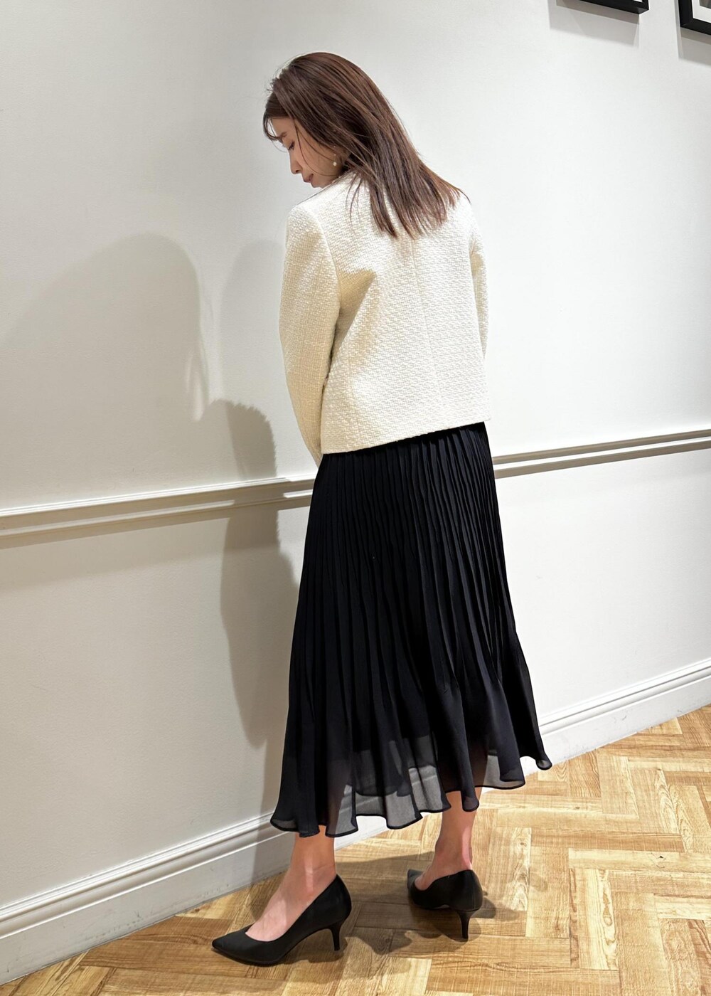 ブラック系のパンプス、ブルー系のワンピース、ホワイト系のノーカラージャケットを着用したレディースの冬コーディネートの3枚目の写真