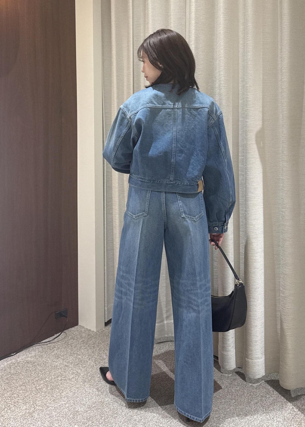 ブラック系のショルダーバッグ、ブルー系のデニムパンツ、ブルー系のデニムジャケットを着用したレディースの春コーディネートの3枚目の写真