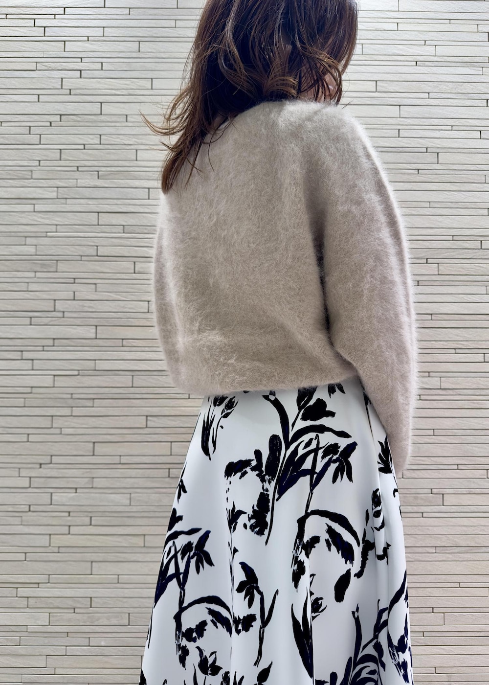 パープル系のハンドバッグ、ブラック系のブーツ、ベージュ系のニット/セーターを着用したレディースの秋コーディネートの4枚目の写真