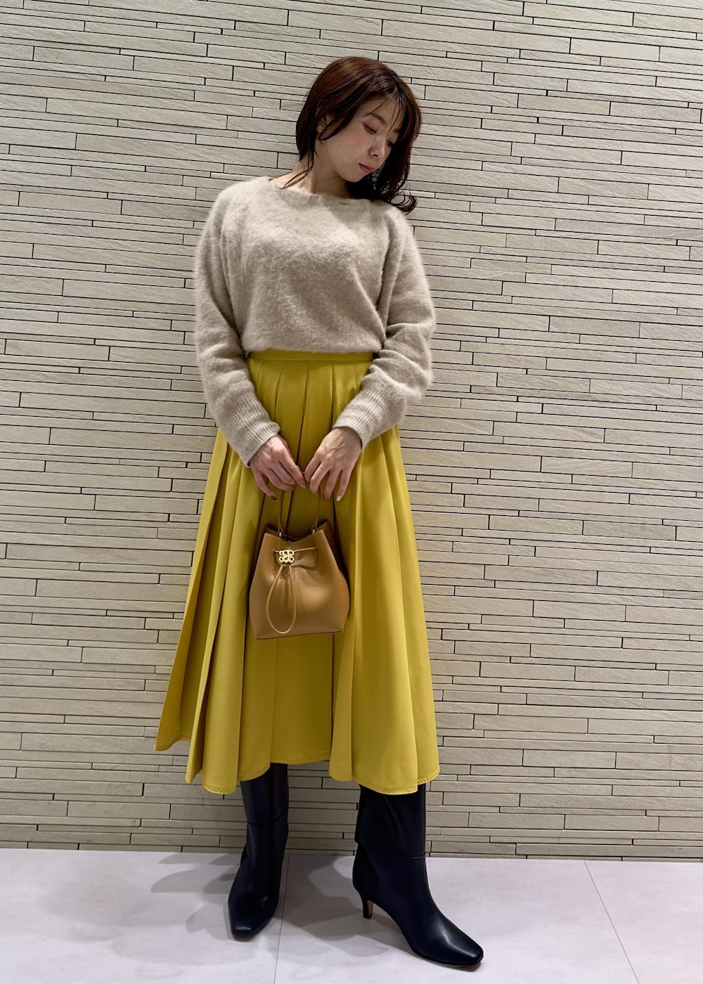 ブラック系のブーツ、ブラック系のその他アウター、イエロー系のハンドバッグを着用したレディースの冬コーディネートの6枚目の写真